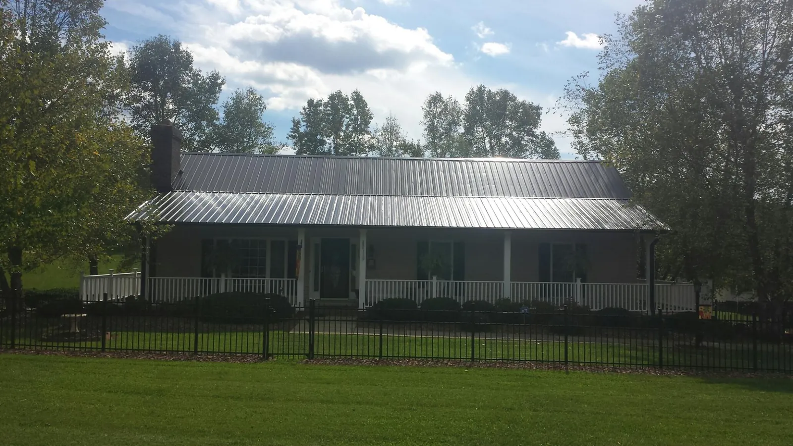 Gray metal roof on a brick ranch with a full width front porch — Gutter Guard Installation work by our crew in Fairview