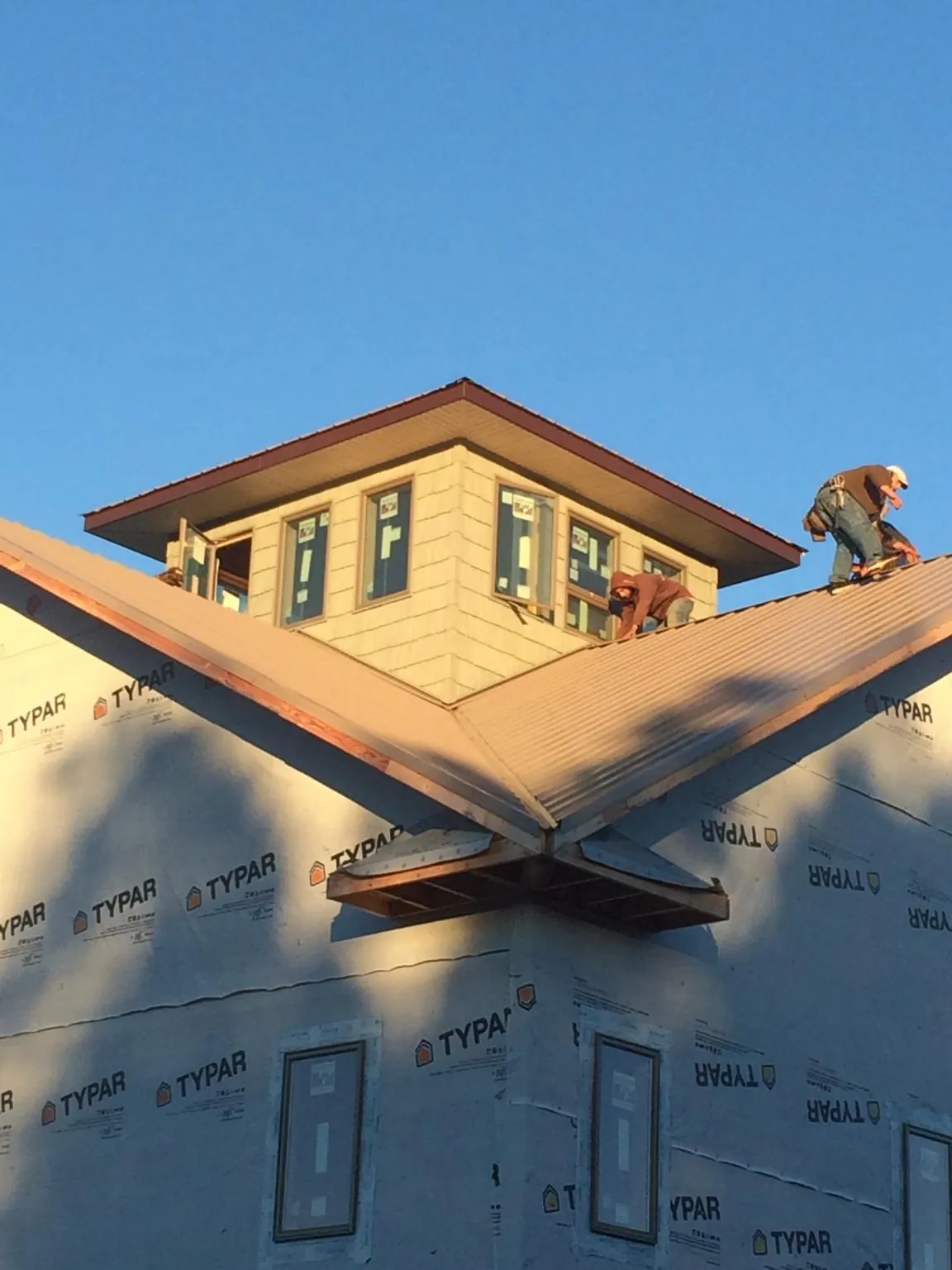 Roofers working around a rooftop cupola on a new metal roof at sunset — Roof Waterproofing in Fairview by Roofing Brothers